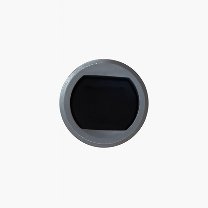 Round metallic object with a black center on a white background