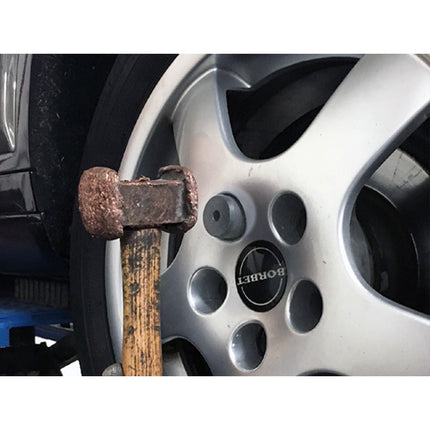 locking wheel nut removal tool shown being used on a car wheel using a hammer to strike the holder