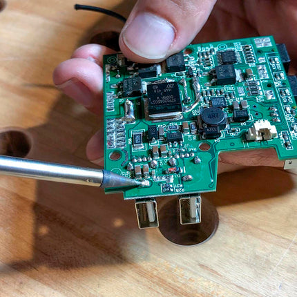 close up of soldering iron being used on a circuit board